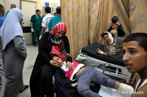 Palestinians whom medics said were wounded in Israeli shelling at a U.N-run school sheltering Palestinian refugees, sit at a hospital in the northern Gaza Strip July 24, 2014. At least 15 people were killed and many woun...