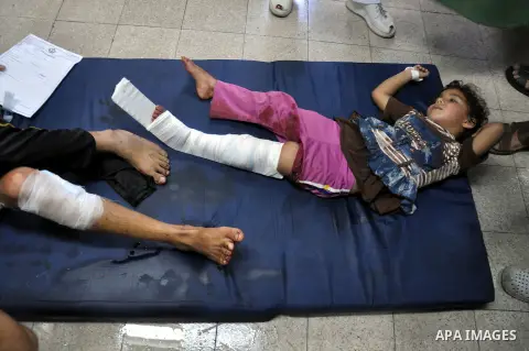 Palestinians whom medics said were wounded in Israeli shelling at a U.N-run school sheltering Palestinian refugees, sit at a hospital in the northern Gaza Strip July 24, 2014. At least 15 people were killed and many woun...