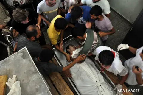 Palestinians mourn gather the body of Palestinian man, who medics said was killed in Israeli shelling at a U.N-run school sheltering Palestinian refugees, mourn outside a hospital morgue in the northern Gaza Strip July 2...