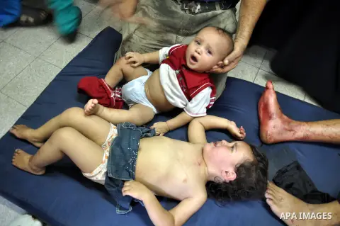 Palestinians whom medics said were wounded in Israeli shelling at a U.N-run school sheltering Palestinian refugees, sit at a hospital in the northern Gaza Strip July 24, 2014. At least 15 people were killed and many woun...