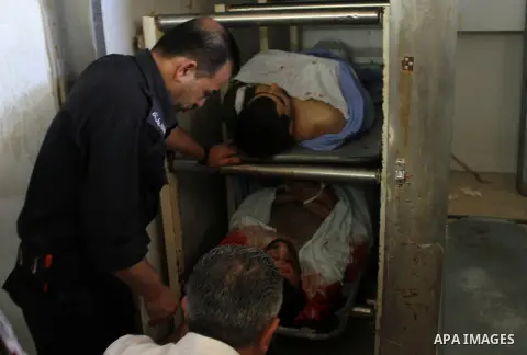 A Palestinian policeman stands next to the bodies of Khaled Odeh, 21, (up) and Tayeb Shehada, 21, killed during a protest in West Bank village of Hawara, while at the morgue at Rafidiyeh Hospital in the West Bank city of...