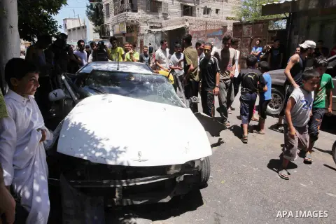 Palestinian men gather behind a car in which at least four people were injured shortly after it was hit by an Israeli airstrike in Gaza, 25 July 2014. More than 820 Palestinians have been killed in Gaza since the start o...
