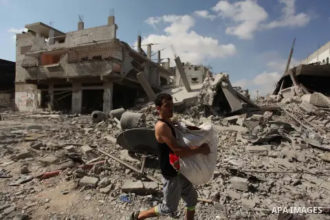 A Palestinian man carries his belongings as he walks past destroyed houses in the Shejaia neighborhood, which witnesses said was heavily hit by Israeli shelling and air strikes during an Israeli offensive, in Gaza City J...