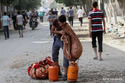 A Palestinian man carries his belongings as he walks past destroyed houses in the Shejaia neighbourhood, which witnesses said was heavily hit by Israeli shelling and air strikes during Israeli offensive, in Gaza City Jul...