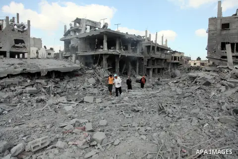 Palestinians walk on the rubble as they enter the northern district of Beit Hanun to check their homes in the Gaza Strip during an humanitarian truce on July 26, 2014. Palestinians retrieved dozens of bodies from the rub...