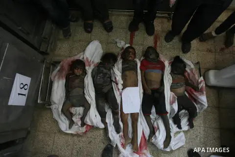 Palestinian gather around the bodies of Palestinian children from the al-Najar family, who medics said were killed by an Israeli air strike on their house, at a hospital morgue in Khan Younis in the southern Gaza Strip J...