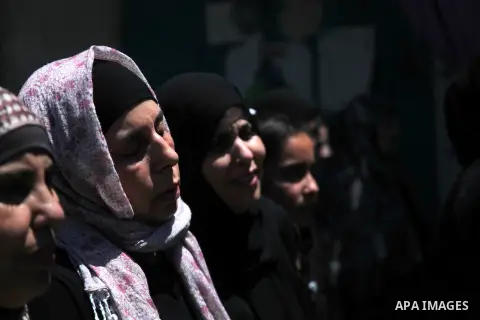 Palestinian women grieve over the body of Eid Fadhelat, 32, who was injured during clashes with Israeli soldiers Friday, during his funeral at Al-Arrub refugee camp near Hebron city in the West Bank on Saturday, July 26,...