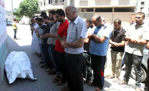 Mourners pray over the body of a Palestinian man, who medics said was killed in an Israeli shelling, at a street in Gaza City on July 26, 2014. Israeli forces have succeeded in destroying at least 1,900 houses and 22,800...