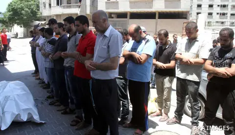 Mourners pray over the body of a Palestinian man, who medics said was killed in an Israeli shelling, at a street in Gaza City on July 26, 2014. Israeli forces have succeeded in destroying at least 1,900 houses and 22,800...