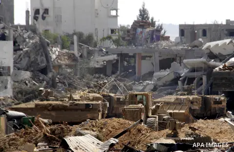An Israeli military tank patrols amid of rubble of destroyed buildings at al-Shijaiyah district in the eastern Gaza City on July 26, 2014. Israeli troops remained in place across the Gaza Strip and continued to search fo...