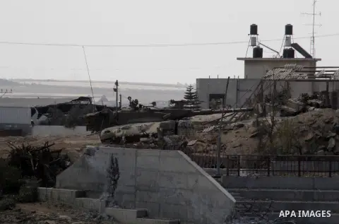 An Israeli military tank patrols amid of rubble of destroyed buildings at al-Shijaiyah district in the eastern Gaza City on July 26, 2014. Israeli troops remained in place across the Gaza Strip and continued to search fo...
