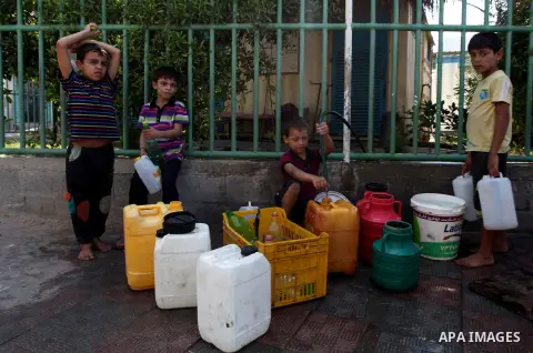 Palestinians children fill plastic bottles and water containers with drinking water from a public tap in Jabalia in the northern Gaza Strip on July 27, 2014. Three Palestinians were killed in shelling as the Israeli mili...