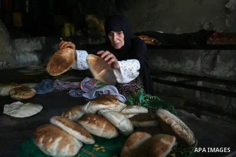 A Palestinian woman bakes bread in a traditional bakery stove in Rafah in the southern Gaza Strip July 27, 2014. More than half of Gaza's population, 1.2 million people, currently were affected by lack of adequate access...