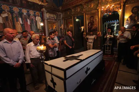Palestinian relatives and friends of Jalila Ayad, a Christian woman whose body was found under the rubble of her home after an Israeli airstike, pray over her coffin during a religious service as part of her funeral on J...