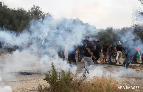Palestinian protesters run for cover from tear gas fired by Israeli security forces during clashes in following the Eid al-Fitr prayer in a protest against the Israeli military operation on Gaza Strip, in the West Bank v...