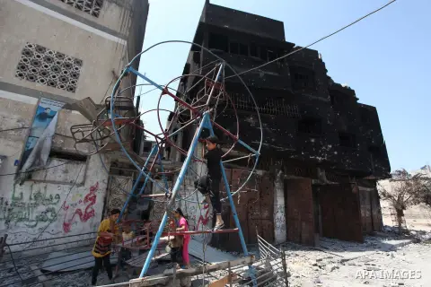 Palestinian children play near a damaged mini ferris wheel in the wartorn Shejaiya district of Gaza City on July 28, 2014 on the first day of Eid al-Fitr holiday. The Muslim three-day Eid al-Fitr festival, that marks the...