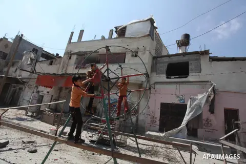 Palestinian children play near a damaged mini ferris wheel in the wartorn Shejaiya district of Gaza City on July 28, 2014 on the first day of Eid al-Fitr holiday. The Muslim three-day Eid al-Fitr festival, that marks the...