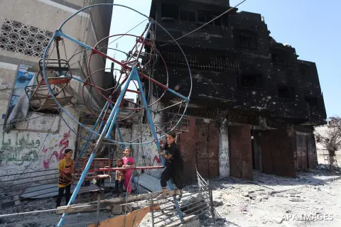 Palestinian children play near a damaged mini ferris wheel in the wartorn Shejaiya district of Gaza City on July 28, 2014 on the first day of Eid al-Fitr holiday. The Muslim three-day Eid al-Fitr festival, that marks the...