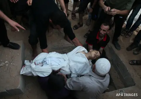 Palestinian men bury the body of a boy who was killed in an explosion, at a cemetery in Gaza City July 28, 2014. At least 10 Palestinians are killed and more than 40 are injured in two Israeli airstrikes in the Gaza Stri...