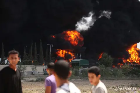 Palestinian men stand looking as flames engulf the fuel tanks of the only power plant supplying electricity to the Gaza Strip after it was hit by overnight Israeli shelling, on July 29, 2014, in the south of Gaza City. T...