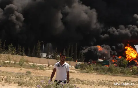 Palestinian men stand looking as flames engulf the fuel tanks of the only power plant supplying electricity to the Gaza Strip after it was hit by overnight Israeli shelling, on July 29, 2014, in the south of Gaza City. T...