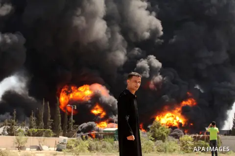 Palestinian men stand looking as flames engulf the fuel tanks of the only power plant supplying electricity to the Gaza Strip after it was hit by overnight Israeli shelling, on July 29, 2014, in the south of Gaza City. T...