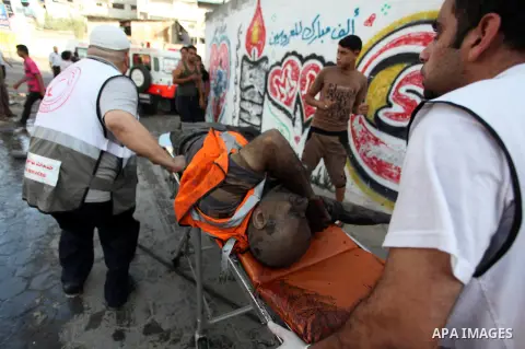 Palestinian paramedics move a victim of an Israeli air strike on a market place to an ambulance in the Shejaiya neighbourhood near Gaza City on July 30, 2014. At least 15 people were killed and 200 people wounded in an I...