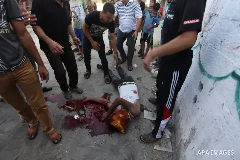 Palestinian paramedics move a victim of an Israeli air strike on a market place to an ambulance in the Shejaiya neighbourhood near Gaza City on July 30, 2014. At least 15 people were killed and 200 people wounded in an I...