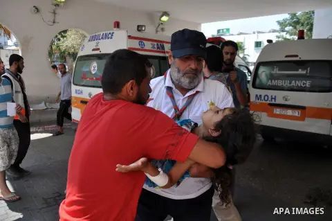 Palestinian paramedics move a victim of an Israeli air strike on a market place to an ambulance in the Shejaiya neighbourhood near Gaza City on July 30, 2014. At least 15 people were killed and 200 people wounded in an I...