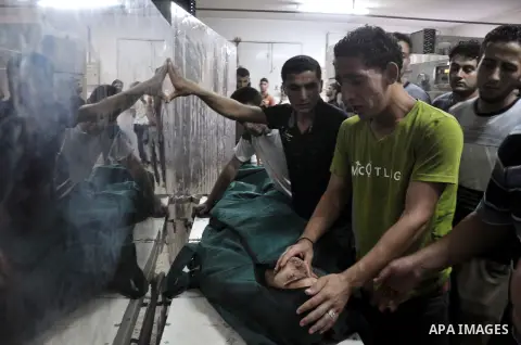 Palestinians look at the body of Palestinian man, whom medics said was killed in an Israeli in Shijaiyah neighborhood, to an emergency room at Shifa Hospital, in Gaza City, Wednesday, July 30, 2014. Photo by Mohammed Tal...