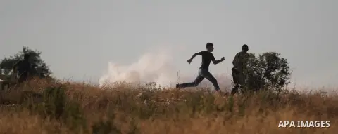 Palestinian protesters run for cover from tear-gas during clashes with Israeli soldiers following a demonstration in the West Bank village of Bilin, on July 31, 2014, in support of Palestinians from the Gaza Strip. Israe...