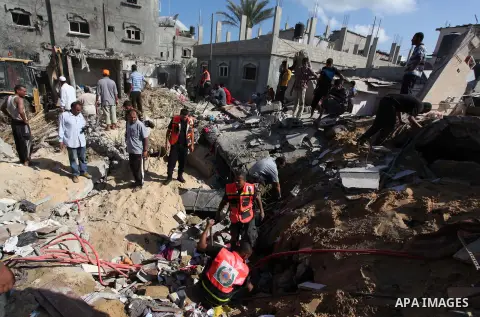 Rescue workers search for victims as Palestinians gather around the wreckage of a house, which witnesses said was destroyed in an Israeli air strike that killed at least five members from the al-Khattab family, in Deir a...