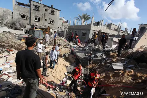 Rescue workers search for victims as Palestinians gather around the wreckage of a house, which witnesses said was destroyed in an Israeli air strike that killed at least five members from the al-Khattab family, in Deir a...