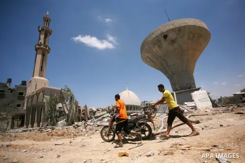 Palestinians walk past a mosque and water tower damaged by what police said were Israeli air strikes and shelling in Khuzaa, east of Khan Younis, in the southern Gaza Strip August 3, 2014. An Israeli air strike killed at...