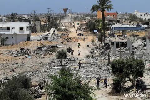 Palestinians walk past a mosque and water tower damaged by what police said were Israeli air strikes and shelling in Khuzaa, east of Khan Younis, in the southern Gaza Strip August 3, 2014. An Israeli air strike killed at...