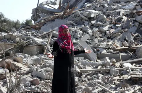 A Palestinian woman gestures as she walks past a houses damaged by what police said were Israeli air strikes and shelling in Khuzaa, east of Khan Younis, in the southern Gaza Strip August 3, 2014. An Israeli air strike k...