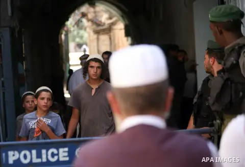 Palestinians stand in front of Israeli policemen as they block a road that leads to the al-Aqsa mosque compound, in Jerusalem's Old City on August 05, 2014. Israeli policemen closed the mosque's main gates and allowed sm...