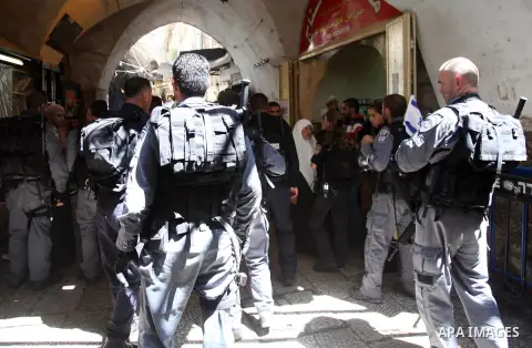 Palestinians stand in front of Israeli policemen as they block a road that leads to the al-Aqsa mosque compound, in Jerusalem's Old City on August 05, 2014. Israeli policemen closed the mosque's main gates and allowed sm...