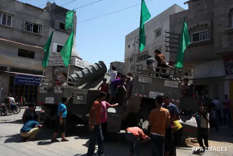 Palestinian children play on the remains of a destroyed Israeli military vehicle, in the east of Khan Younis in the southern Gaza Strip August 5, 2014. Israel pulled its ground forces out of the Gaza Strip on Tuesday and...