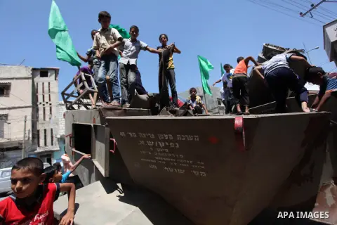 Palestinian children play on the remains of a destroyed Israeli military vehicle, in the east of Khan Younis in the southern Gaza Strip August 5, 2014. Israel pulled its ground forces out of the Gaza Strip on Tuesday and...