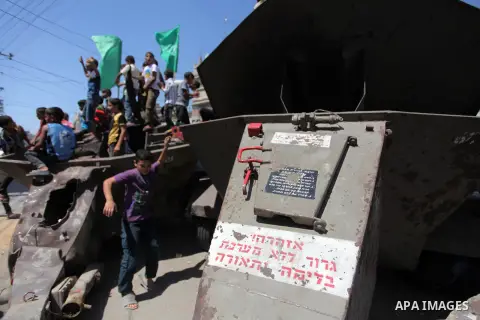 Palestinian children play on the remains of a destroyed Israeli military vehicle, in the east of Khan Younis in the southern Gaza Strip August 5, 2014. Israel pulled its ground forces out of the Gaza Strip on Tuesday and...