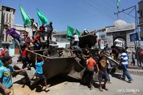 Palestinian children play on the remains of a destroyed Israeli military vehicle, in the east of Khan Younis in the southern Gaza Strip August 5, 2014. Israel pulled its ground forces out of the Gaza Strip on Tuesday and...