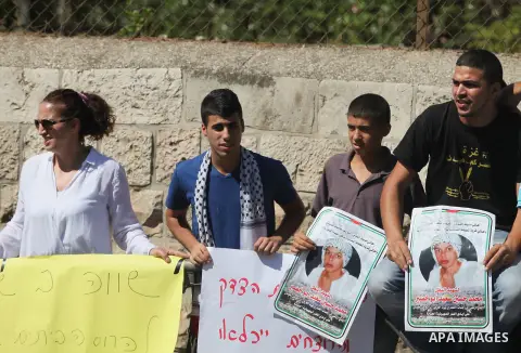 Palestinians hold signs and posters depicting Palestinian teen Mohammed Abu Khudair during a protest outside Jerusalem District Court August 6, 2014. Jerusalem District Court on Wednesday remanded Yosef Ben David, one of...