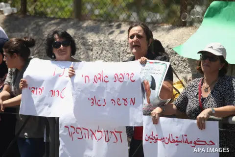 Palestinians hold signs and posters depicting Palestinian teen Mohammed Abu Khudair during a protest outside Jerusalem District Court August 6, 2014. Jerusalem District Court on Wednesday remanded Yosef Ben David, one of...