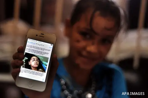 A Palestinian girl, who medics said was injured during the Israeli military offensive on Gaza Strip, shows her picture in a mobile phone as she lies on a bed at al-shifa hospital in Gaza City on August 05, 2014. The ceas...