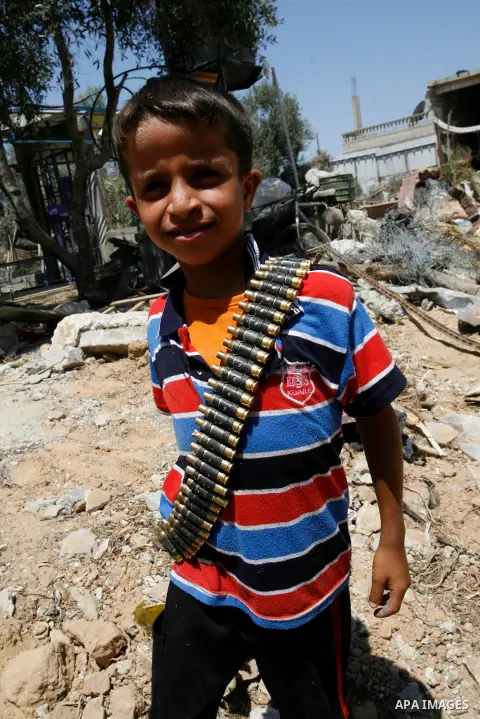 A Palestinian boy holds a bullet belt, left empty by the Israeli army, following the Israeli offensive on Abasan, east of the southern Gaza Strip town of Khan Yunis and close to the border with Israel on August 7, 2014....