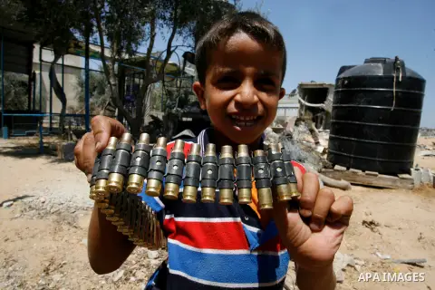 A Palestinian boy holds a bullet belt, left empty by the Israeli army, following the Israeli offensive on Abasan, east of the southern Gaza Strip town of Khan Yunis and close to the border with Israel on August 7, 2014....
