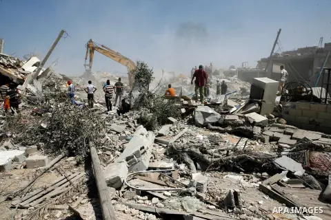 Palestinians watch on as rescuers search for victims under the rubble of a house which was destroyed following an Israeli air strike on Abasan, east of the southern Gaza Strip town of Khan Yunis and close to the border w...