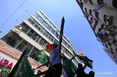 A Palestinian man carries a mock Qassam missile and waves the national flag during a rally in support of the Hamas movement following Friday prayers, in the West Bank city of Ramallah on August 8, 2014. The head of a Pal...