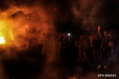 Palestinians look as firefighters try to extinguish fire from soap factory that caught fire moments after it was hit by an Israeli airstrike in Gaza City August 10, 2014. Palestinian and Israeli negotiators on Sunday sai...